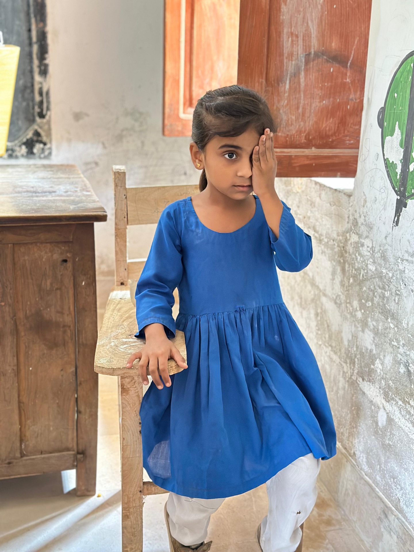 Young Pakistani pupil performs vision check by covering one eye