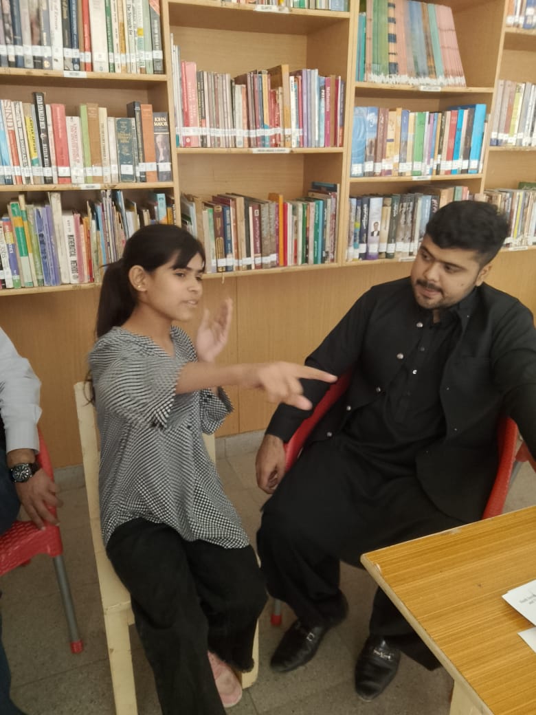 Pakistani student in conversation with eye care provider in a school library