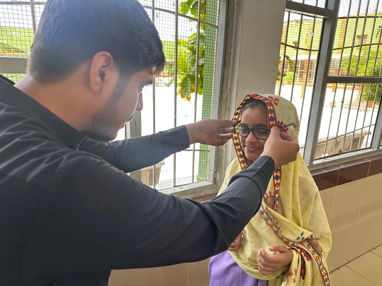 Optometrist fits a Pakistani student with her new prescription spectacles