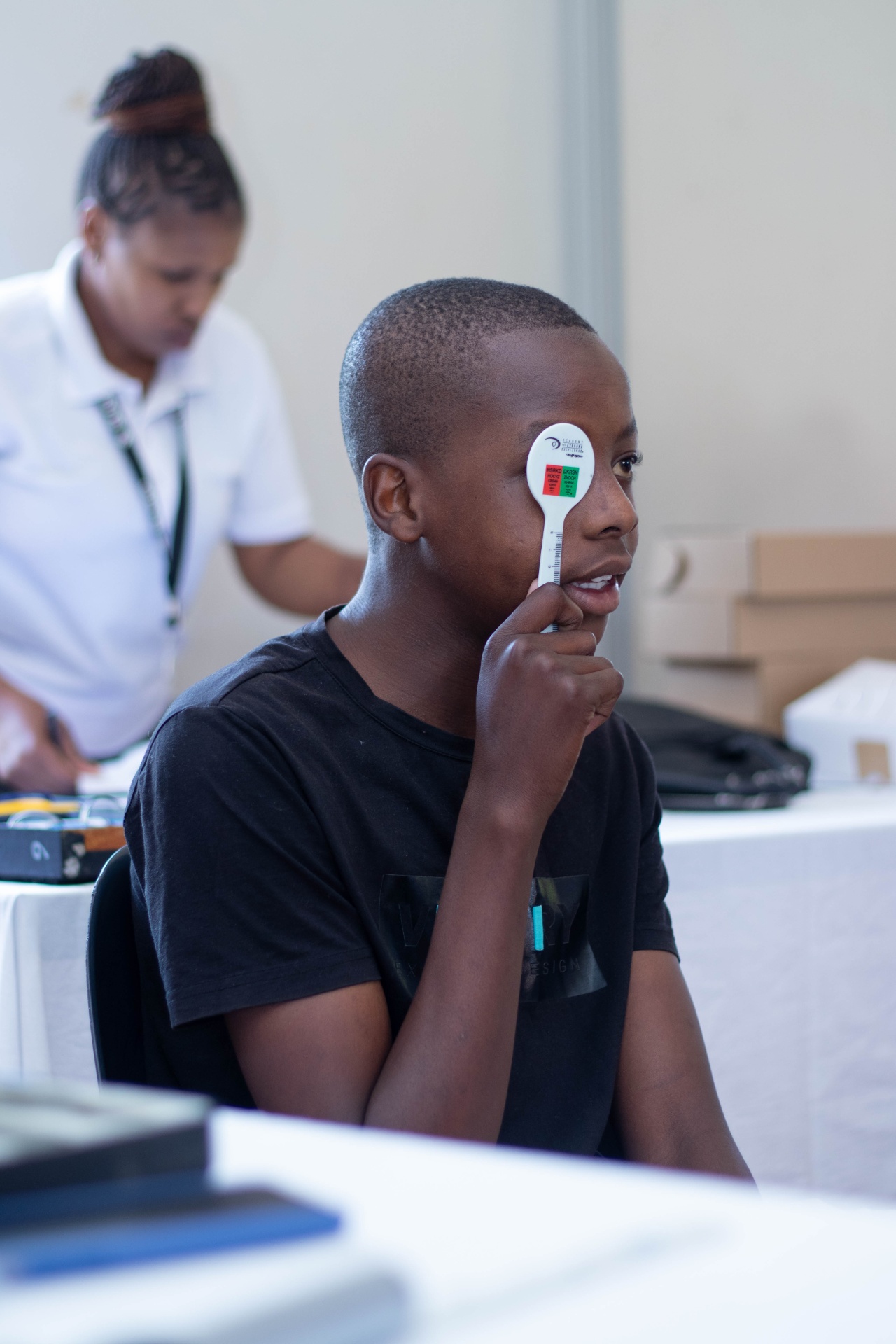 South African student covers one eye with an occluder during school vision screening