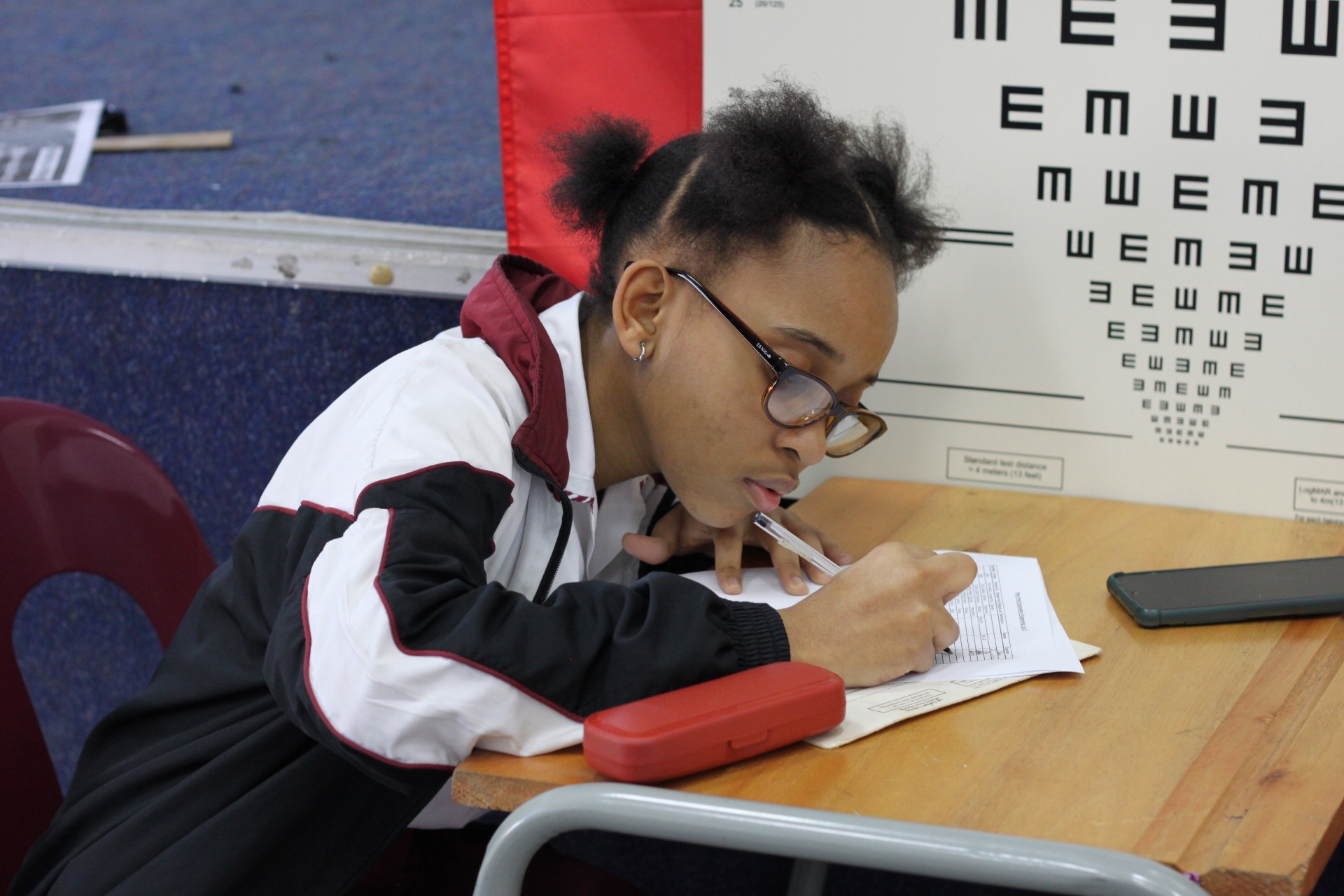 Student writes at her desk wearing her new prescription glasses