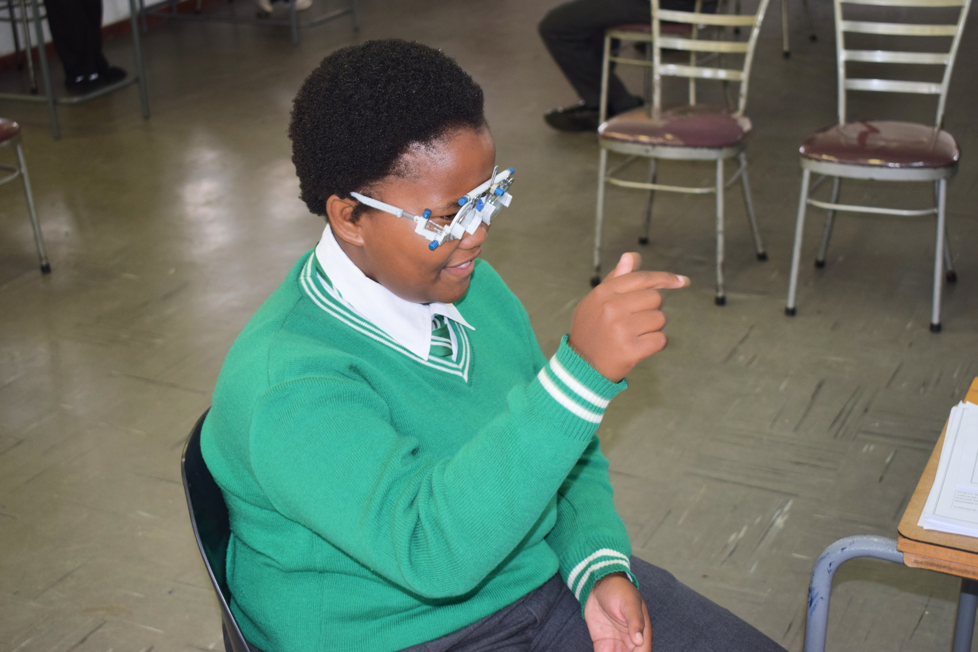 Student in green school uniform smiles while wearing trial frame, South Africa